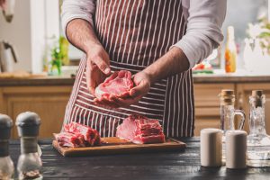 cozinheiro com um pedaço de chuleta na mão